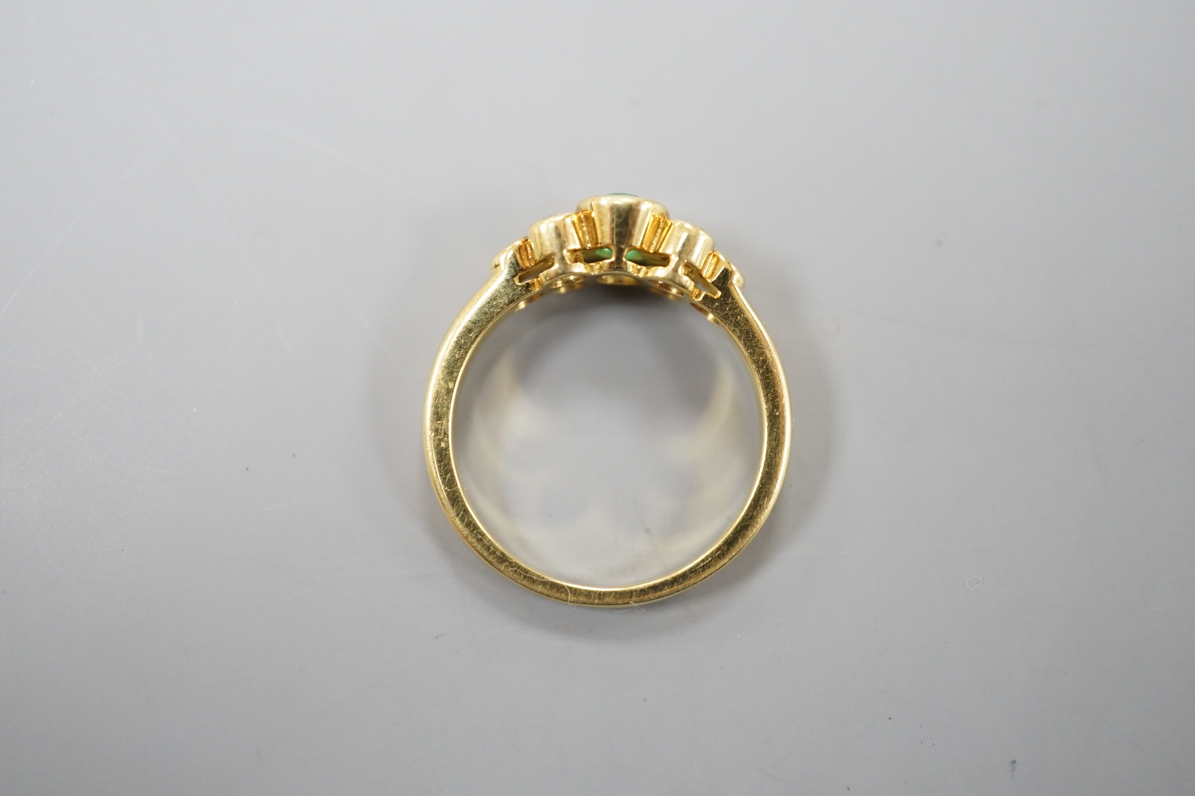 A modern yellow metal and collet set oval cut emerald ring, with six stone diamond set shoulders, size L/M, gross weight 4.1 grams.
